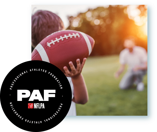 Father and son playing football together outside with NFL player Association logo