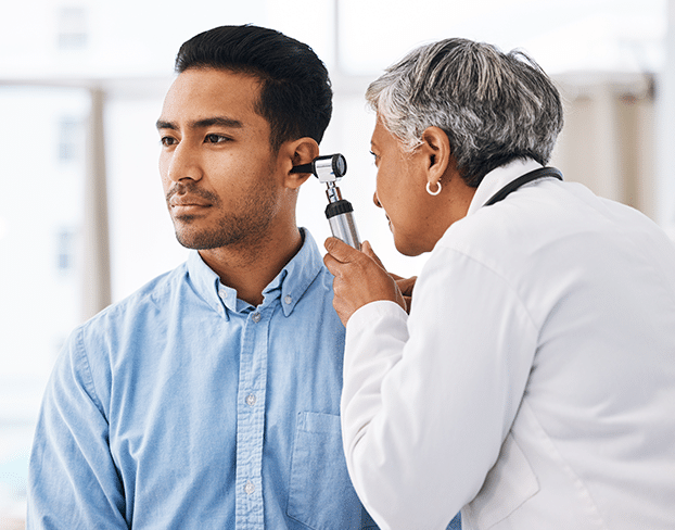 Man dealing with signs of hearing loss getting his ears checked by a hearing specialist