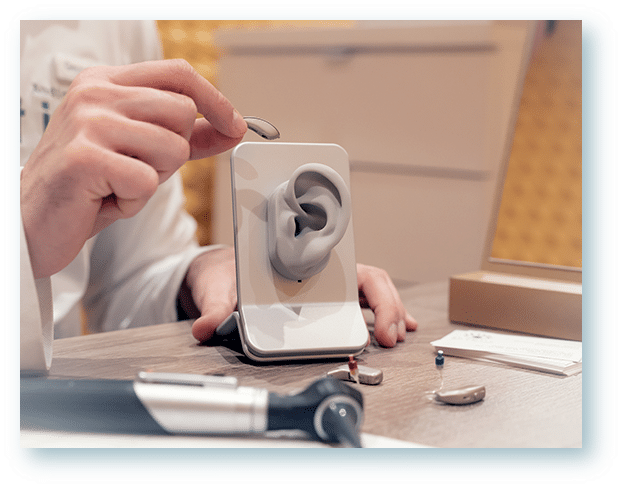 Hearing Instrument Specialist handing a patient their repaired hearing aids